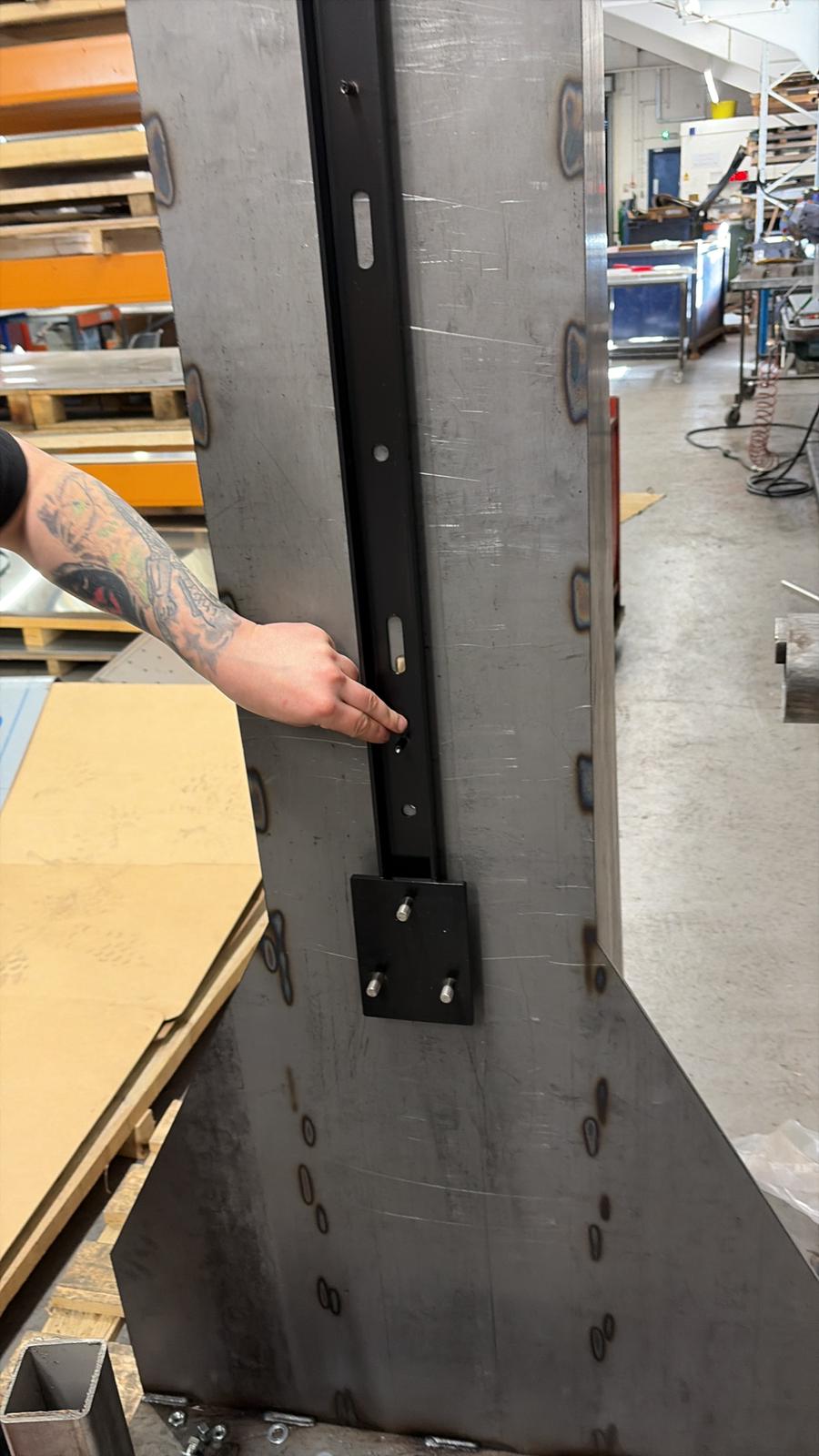 A stainless steel bracket mounted to the in-house load test rig