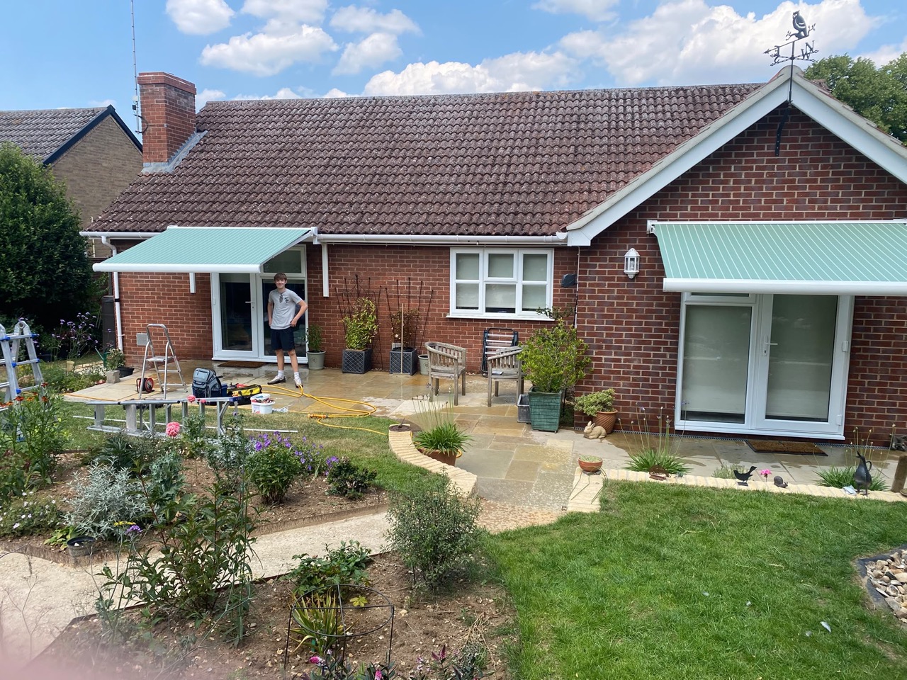 Twin awnings on load-bearing gutter brackets — wide view of a recent UK install