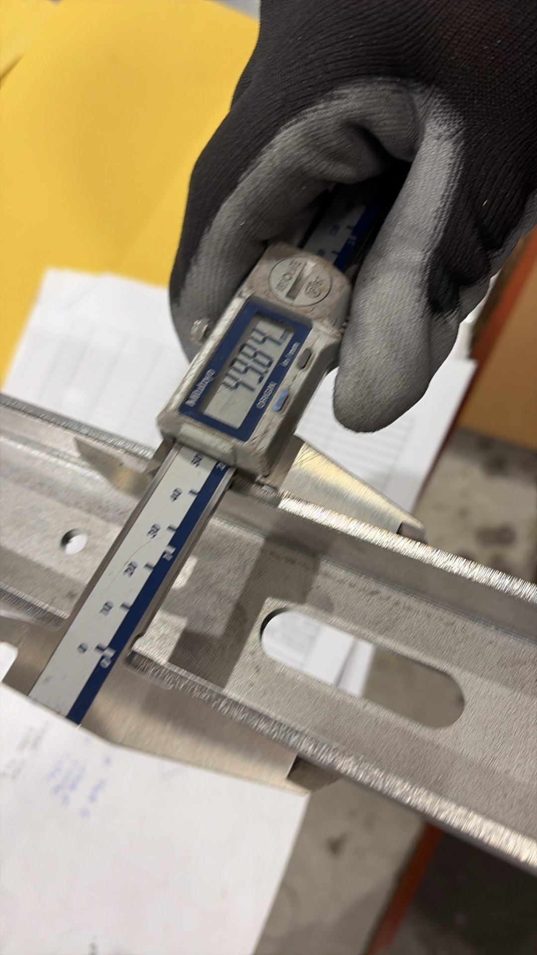 Operator measuring a formed stainless bracket with digital calipers