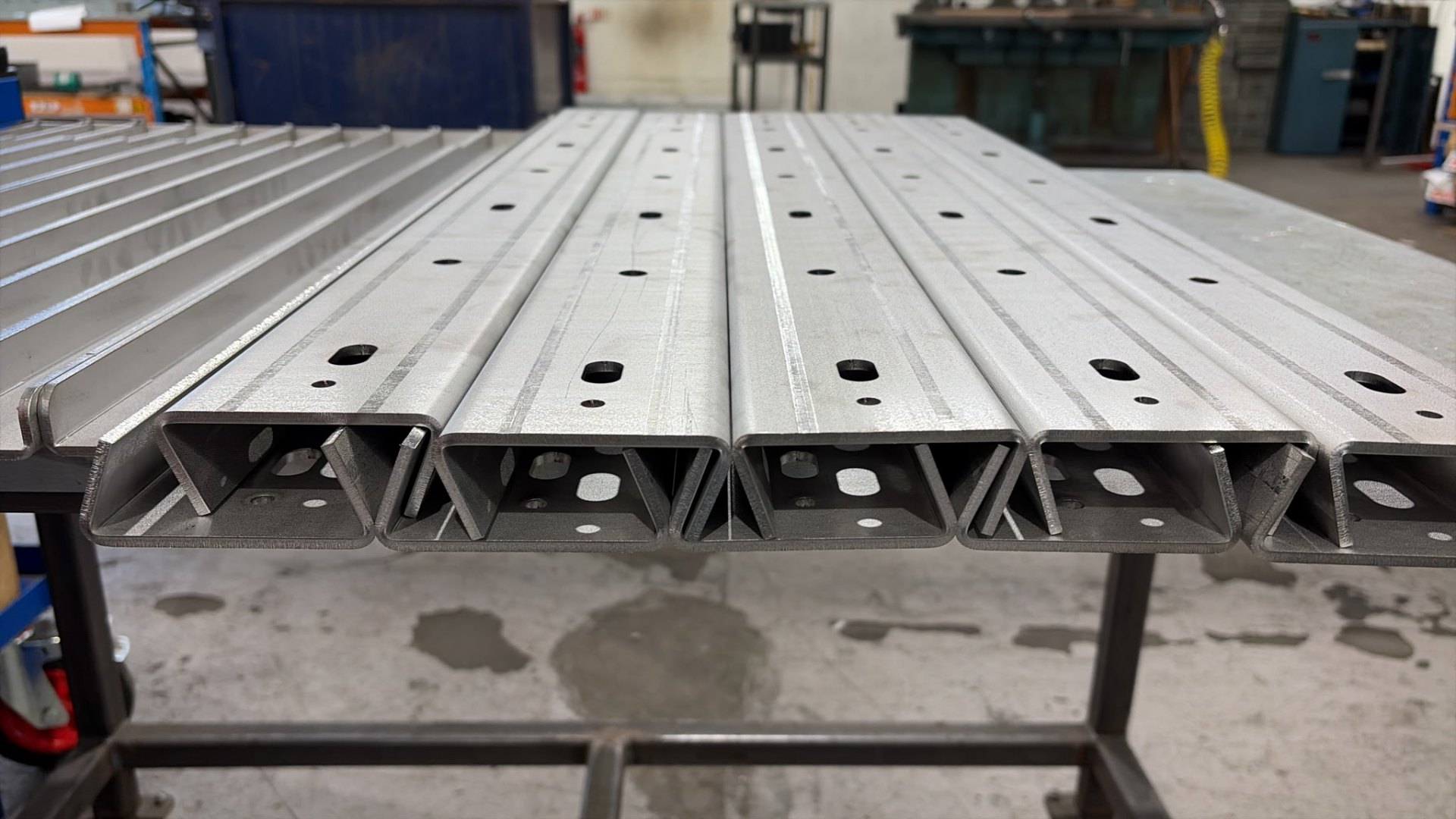 Stacked formed stainless steel bracket profiles showing fixing holes at 150mm centres