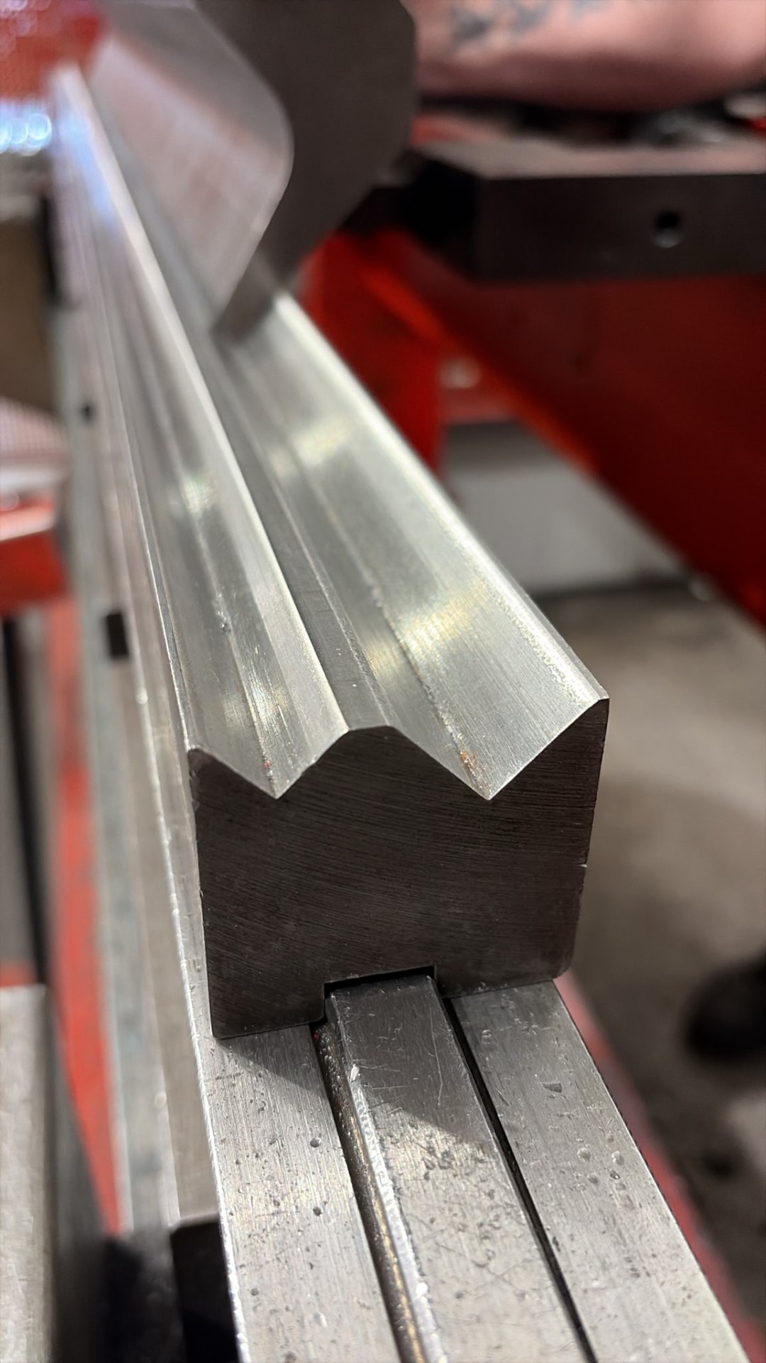 Close-up of press brake tooling forming a stainless steel profile