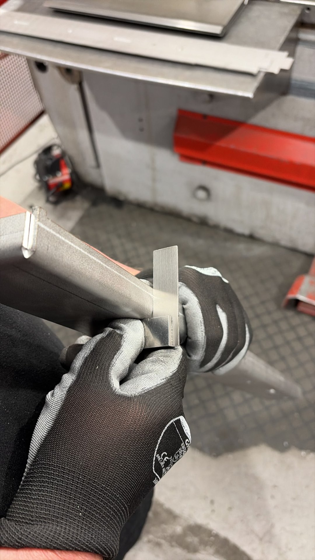 Operator checking the bend angle of a formed stainless steel bracket