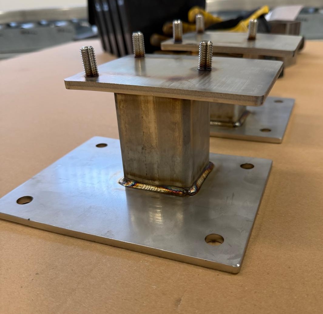 Pipe bracket close-up — clean weld fillet on a 6 mm stainless base plate