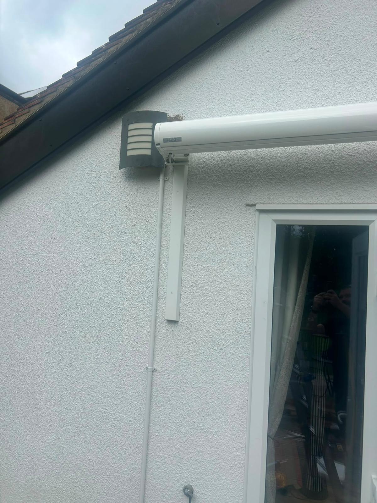 Close-up of LoadBear Standard Spreader Bracket mounted to a rendered wall supporting an awning arm